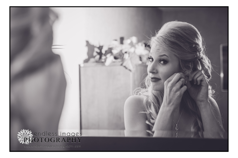 bride adjusts her jewelry in the mirror before wedding